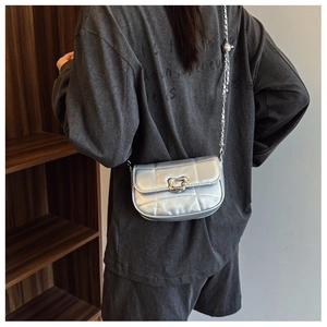 Détail du sac bandoulière argenté matelassé avec chaîne montrant la boucle en U et texture