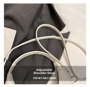 Detail of adjustable shoulder strap on white leather bag with premium metal hardware