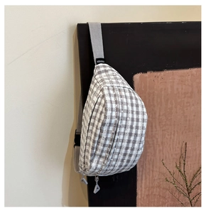 Detail of plaid chest bag with grey woven strap and triangular zipper puller