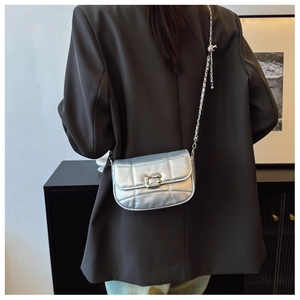 Détail du sac à bandoulière argenté matelassé avec chaîne porté par un mannequin