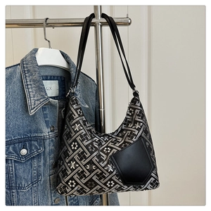 Detail of floral embroidery and leather pocket on a retro black and silver shoulder bag