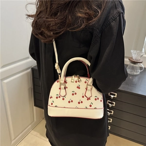 Mini dome bag with red cherry prints and adjustable strap for a trendy stylish look