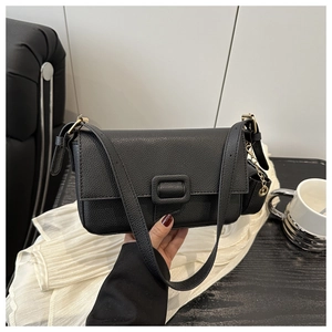Close-up of black litchi textured leather shoulder bag with gold chain and square buckle