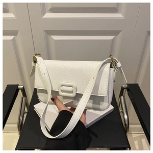 Detailed macro view of white pebble leather crossbody bag with minimalist square buckle