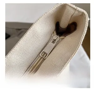 Macro detail of high-density canvas texture and smooth metal zipper on white tote bag