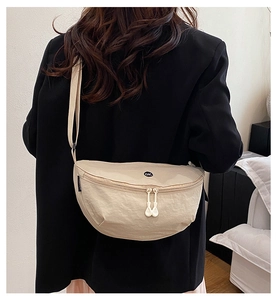 Detail of beige nylon crescent bag with adjustable strap and circular logo on the back