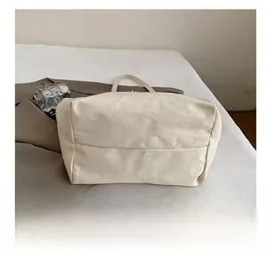 Detail view showing the reinforced wear-resistant bottom of the beige canvas tote bag
