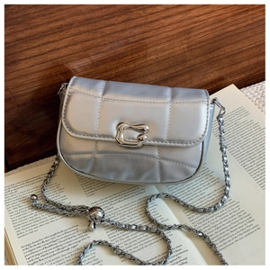 Détail du sac bandoulière argenté matelassé avec chaîne en métal et breloque sphérique