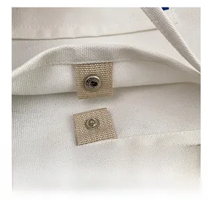 Detail shot of the silver magnetic closure on a minimalist white canvas tote bag