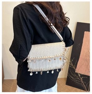 Detail of straw shoulder bag with natural seashells fringe and woven texture finish