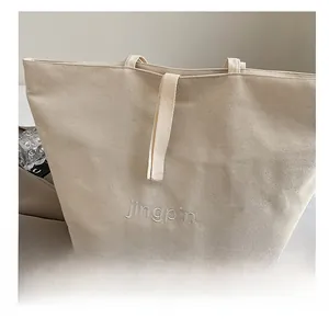 Detail of off-white canvas tote bag with exquisite letter embroidery and wide strap