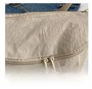 Detail of beige nylon tote bag with dual zippers and circular embroidered OK logo