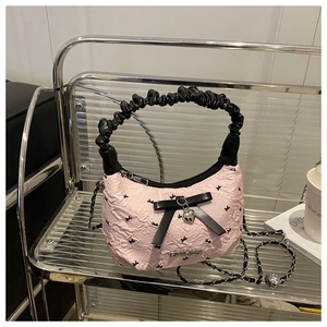 Detail of pink pleated cloud bag featuring black bows and a heart pendant