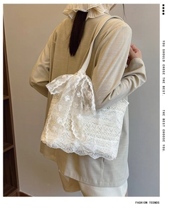 Detailed close-up of white floral lace embroidery and large decorative bow on tote bag