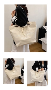 Detail view of large capacity off-white canvas tote bag with black letter print