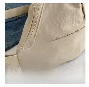 Detail of beige nylon crossbody bag showing the fashion tag and durable stitching