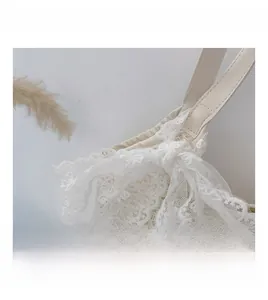 Detailed close-up of white lace tote bag with elegant ruffled trim and decorative ribbon bow