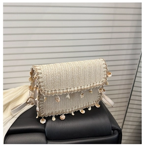Detail of beige straw bag with bohemian shell charms and rectangle flap cover