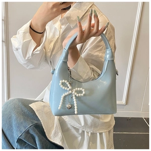 Detail of light blue patent leather handbag with pearl bow charm and silver heart pendant