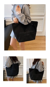 Detail view of large black canvas tote bag with textured embroidery on white shutters background
