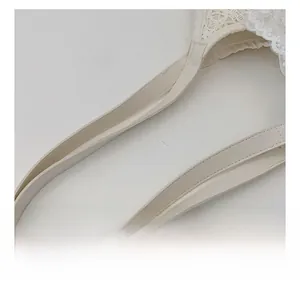 Close-up of cream leather handle and delicate white lace embroidery on a bucket bag