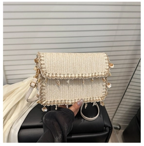 Detail of woven straw bag featuring real shell charms and adjustable white leather strap