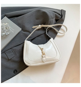 Dettaglio della borsa hobo a mezzaluna bianco crema con fibbia dorata su un blazer grigio