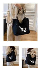 Detail of a large black canvas tote bag with white bag print and fashion label detail
