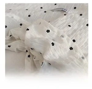 Détail de maille blanche avec motif floral noir et texture plissée sur le sac à bandoulière