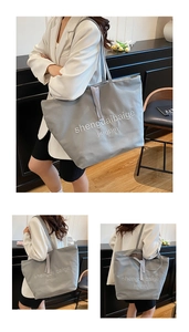 Détail macro des lettres brodées sur un sac cabas en toile grise avec coutures premium