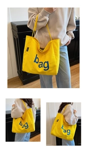 Detail of bright yellow canvas tote bag featuring blue bag print and fashion side label