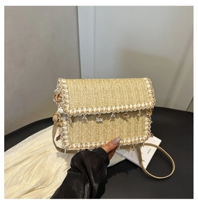 Detailed close-up of straw woven bag with lace trim and natural shell charms
