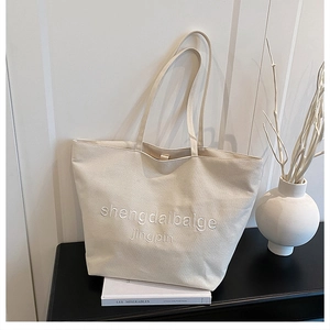 Détail de la broderie 3D blanche sur le sac cabas en toile écru au style minimaliste