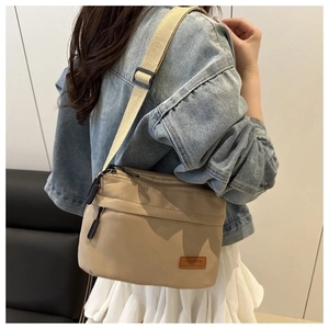 Vue détaillée d'un sac bandoulière en nylon kaki avec sangle réglable et plusieurs compartiments