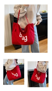 Detail of red canvas tote bag with white bag lettering and reinforced handle stitching