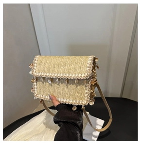 Detail of woven straw crossbody bag featuring scalloped lace trim and shell pendants