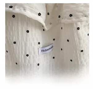 Détail du sac cabas en seersucker blanc à motif floral et étiquette tendance