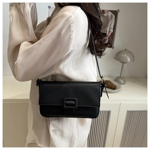 Detail of black lychee grain leather crossbody bag with square buckle decoration