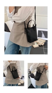Close-up of black litchi texture mini tote bag with a cute smiley face metal charm detail