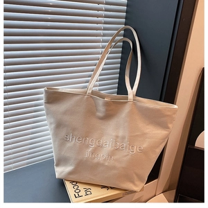 Détail d'un sac cabas en toile blanc cassé avec broderie, design minimal pour étudiantes