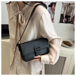 Detail of black lychee grain leather flap bag with rectangular buckle on model