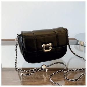 Détail d'un sac bandoulière matelassé noir avec chaîne argentée et boucle métallique
