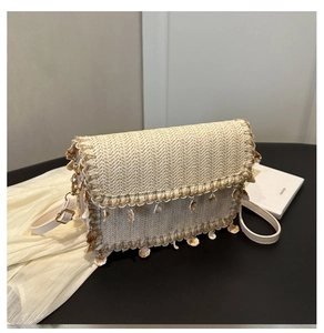 Detail of bohemian straw bag with wave weave pattern and white shell charms decorative fringe