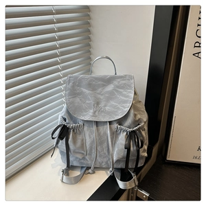 Détail du sac à dos gris clair avec broderie Nika, cordon de serrage et nœud noir