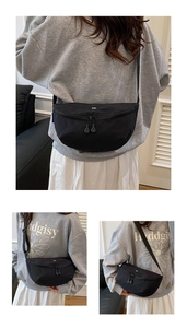 Detail of black crescent crossbody bag with white OK print and adjustable textile strap