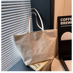 Close-up of cream canvas tote bag with elegant tonal embroidery and premium texture