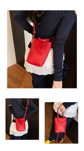 Close-up of red lychee grain leather bucket bag with smiley charm and thin double handles