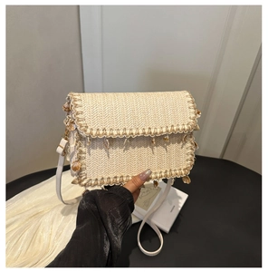 Detailed view of straw shoulder bag featuring shell charm and wavy lace trim edges