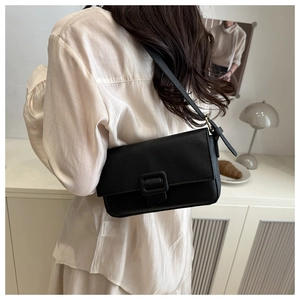 Detail view of black lychee textured leather baguette shoulder bag with square buckle