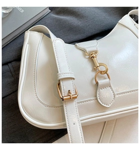 Dettaglio della borsa in pelle verniciata bianca con gancio dorato e tracolla regolabile